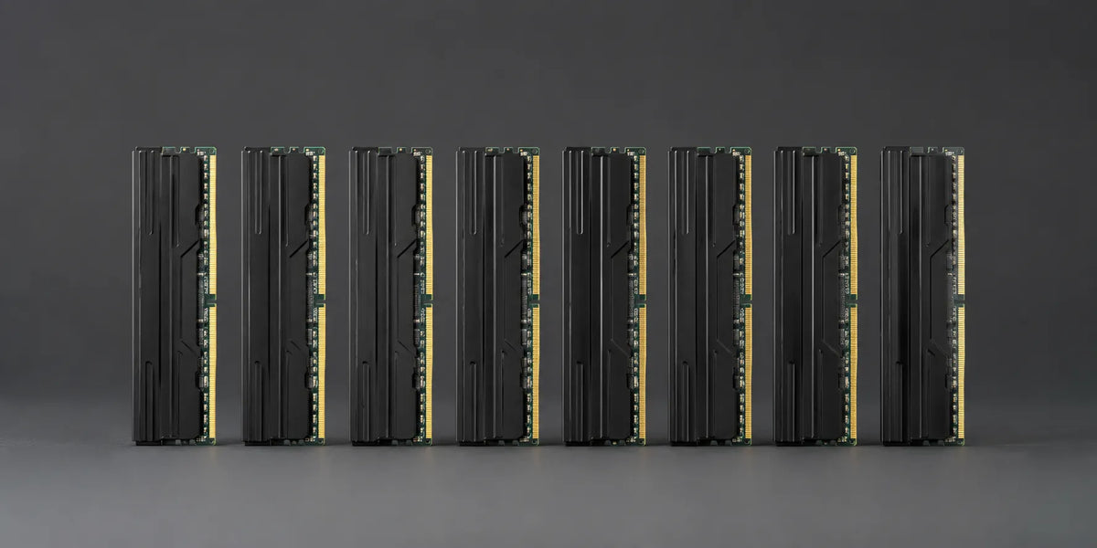 Eight black RAM memory modules with sleek heatsinks arranged vertically in a row against a gray background.